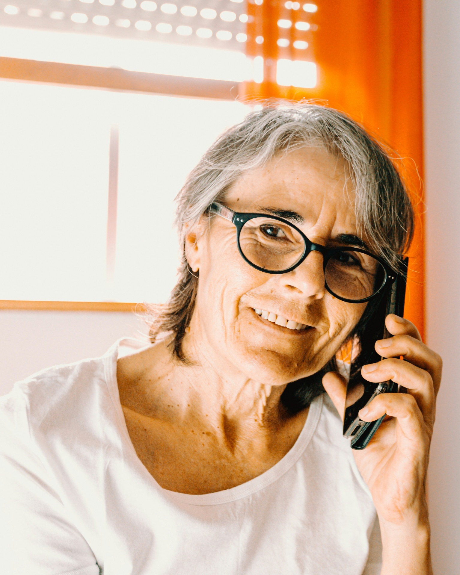 Femme âgée souriante au téléphone